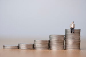 Aging society And saving money for retirement concept ,Old man sitting on coins stacking.