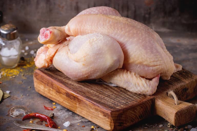 Raw mini Chicken on wooden cutting board with sea salt and different spices over old metal surface